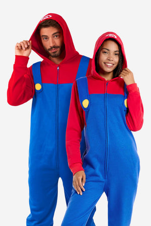 Mann und Frau tragen einen rot-blauen Unisex Onesie für Erwachsene mit Super-Mario-Motiv. Der Onesie ähnelt dem Super-Mario-Outfit.