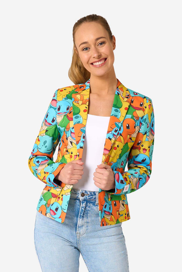 Eine Frau trägt einen mehrfarbigen Pokemon-Blazer, auf dem Figuren wie Pikachu, Squirtle, Charmander und Bulbasaur abgebildet sind. Sie hält die Jacke und lächelt in die Kamera.