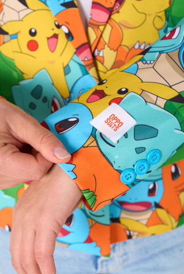 Frauen tragen einen mehrfarbigen Pokemon-Blazer, auf dem Figuren wie Pikachu, Squirtle, Charmander und Bulbasaur zu sehen sind. Nahaufnahme der Ärmel.