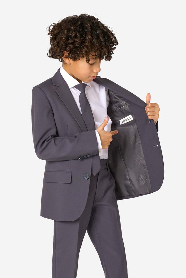 Junge in einem eleganten, anthrazitfarbenen Anzug mit weißem Hemd und selbstbewusstem Lächeln. Perfektes formelles Outfit für besondere Anlässe, Hochzeiten und Partys.