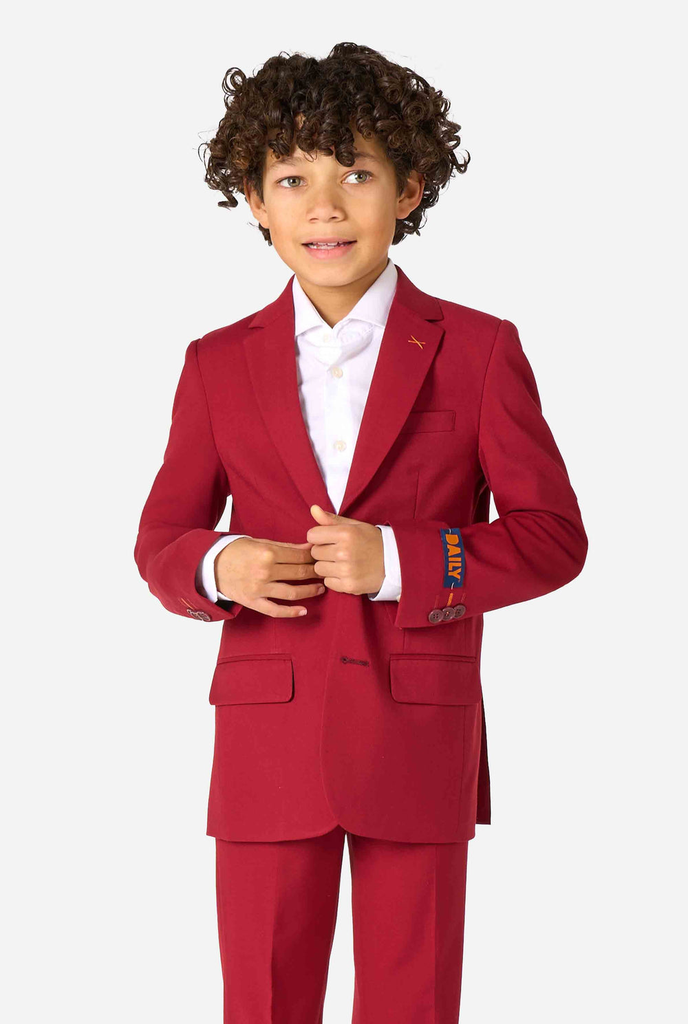 Kind trägt einen stilvollen bordeauxroten Anzug mit weißem Hemd, schaut selbstbewusst. Perfektes festliches Outfit für besondere Anlässe, Hochzeiten und Partys von Jungen.