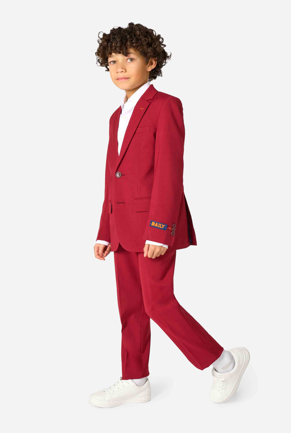 Kind trägt einen stilvollen bordeauxroten Anzug mit weißem Hemd, schaut selbstbewusst. Perfektes festliches Outfit für besondere Anlässe, Hochzeiten und Partys von Jungen.