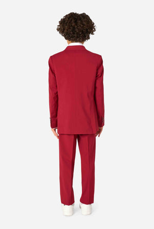 Kind trägt einen stilvollen bordeauxroten Anzug mit weißem Hemd, schaut selbstbewusst. Perfektes festliches Outfit für besondere Anlässe, Hochzeiten und Partys von Jungen. Ansicht von hinten.