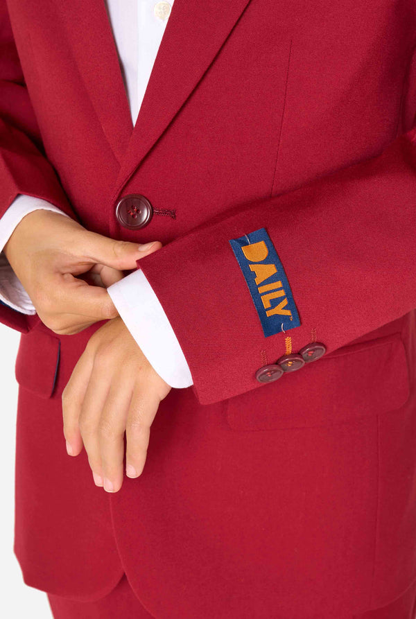 Kind trägt einen stilvollen bordeauxroten Anzug mit weißem Hemd, schaut selbstbewusst. Perfektes festliches Outfit für besondere Anlässe, Hochzeiten und Partys von Jungen. Nahaufnahme des Ärmels.
