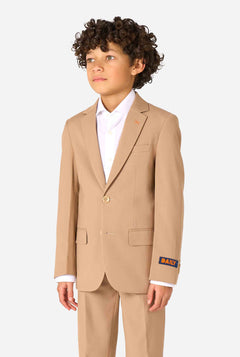 Kind trägt einen stilvollen hellbraunen/beigen Anzug mit weißem Hemd, schaut weg von der Kamera. Perfektes festliches Outfit für besondere Anlässe, Hochzeiten und Partys von Jungen.