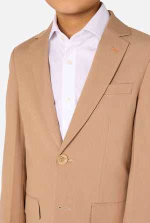 Kind trägt einen stilvollen hellbraunen/beigen Anzug mit weißem Hemd, schaut weg von der Kamera. Perfektes festliches Outfit für besondere Anlässe, Hochzeiten und Partys von Jungen. Fokus auf den Oberkörper.
