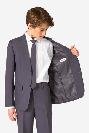 Teenager in einem stylischen anthrazitfarbenen Anzug mit weißem Hemd und selbstbewusstem Lächeln. Perfektes formelles Outfit für besondere Anlässe, Hochzeiten und Partys.