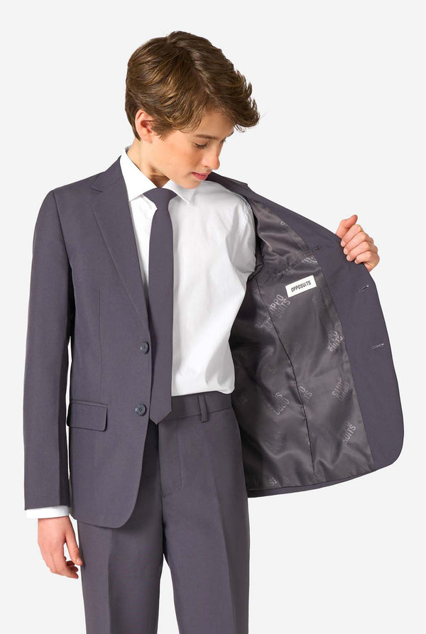 Teenager in einem stylischen anthrazitfarbenen Anzug mit weißem Hemd und selbstbewusstem Lächeln. Perfektes formelles Outfit für besondere Anlässe, Hochzeiten und Partys.