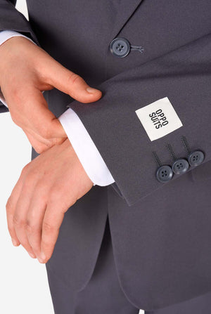 Teenager in einem stylischen anthrazitfarbenen Anzug mit weißem Hemd und selbstbewusstem Lächeln. Perfektes formelles Outfit für besondere Anlässe, Hochzeiten und Partys.