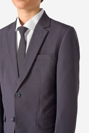 Teenager in einem stylischen anthrazitfarbenen Anzug mit weißem Hemd und selbstbewusstem Lächeln. Perfektes formelles Outfit für besondere Anlässe, Hochzeiten und Partys.