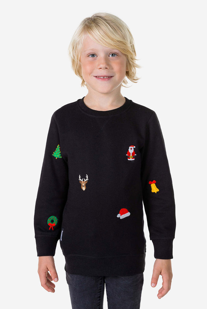 Kind trägt einen schwarzen Weihnachtspullover mit Weihnachtsikonen