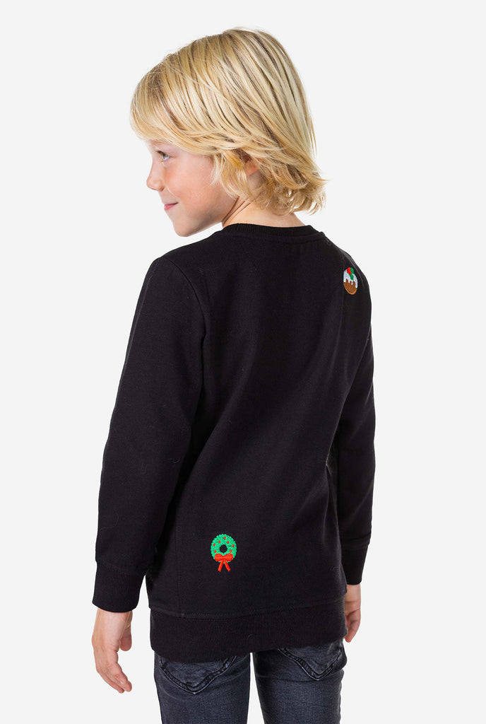 Kind trägt einen schwarzen Weihnachtspullover mit Weihnachtselikonen, Blick von hinten