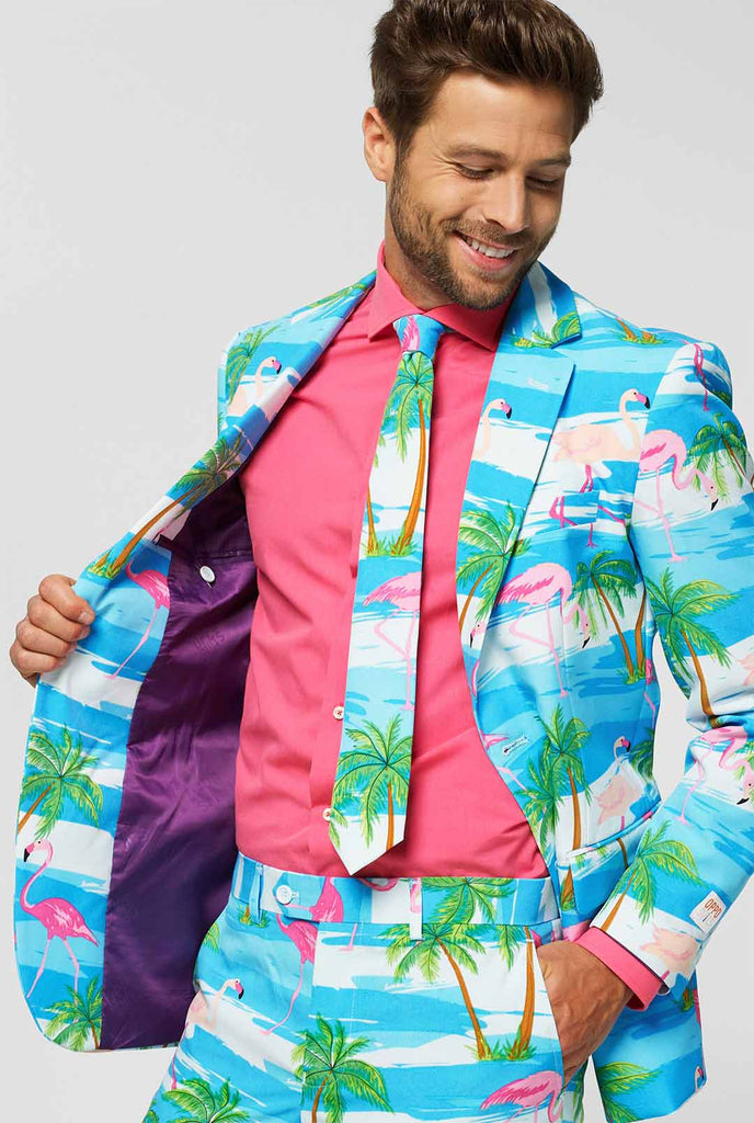 Blauer und weißer Anzug mit tropischem Flamingo -Druck flaminguy vom Mann in der Jacke, der ihn hält, abgenutzt