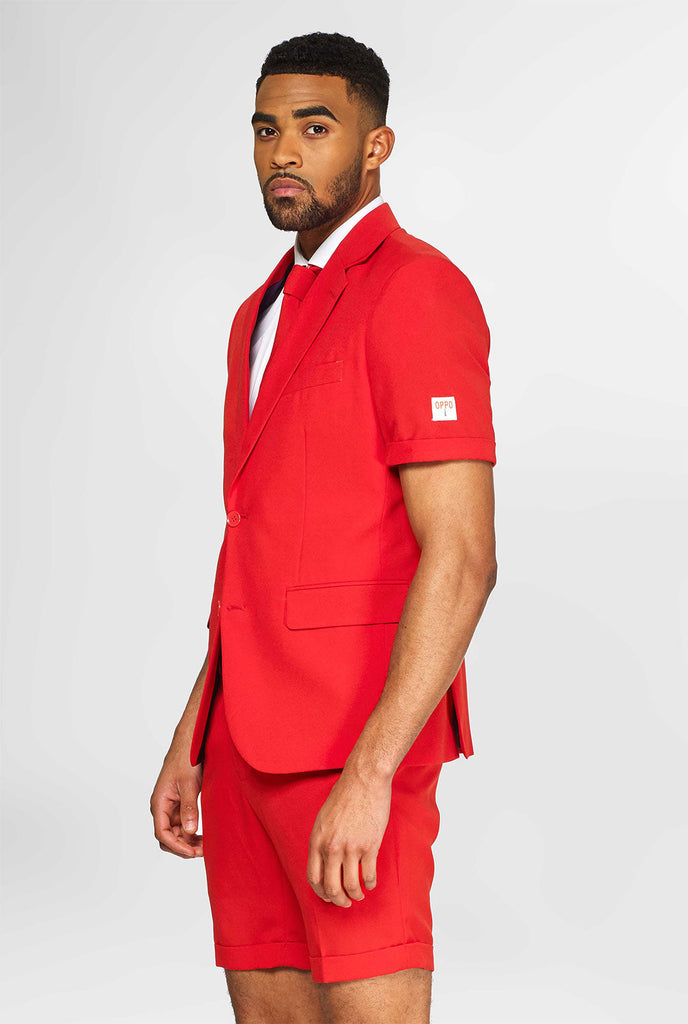 Mann, der einen roten Sommeranzug trägt, bestehend aus Shorts, Jacke und Krawatte
