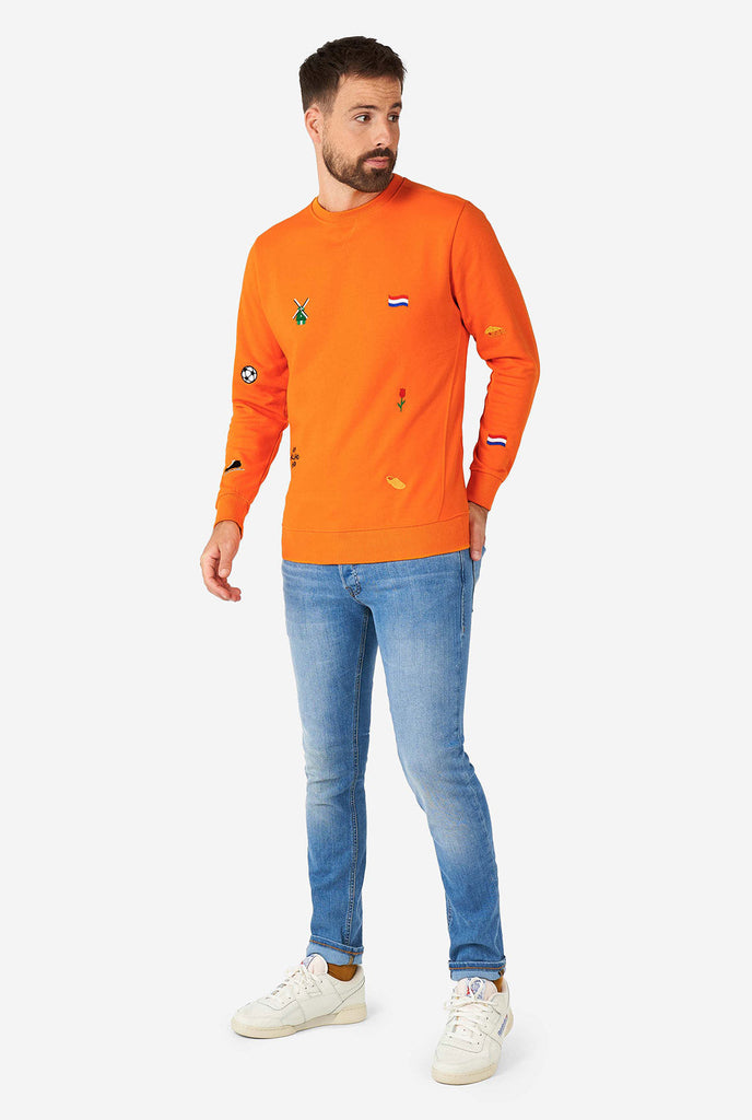 Mann trägt einen orangefarbenen Pullover mit niederländischen Ikonen
