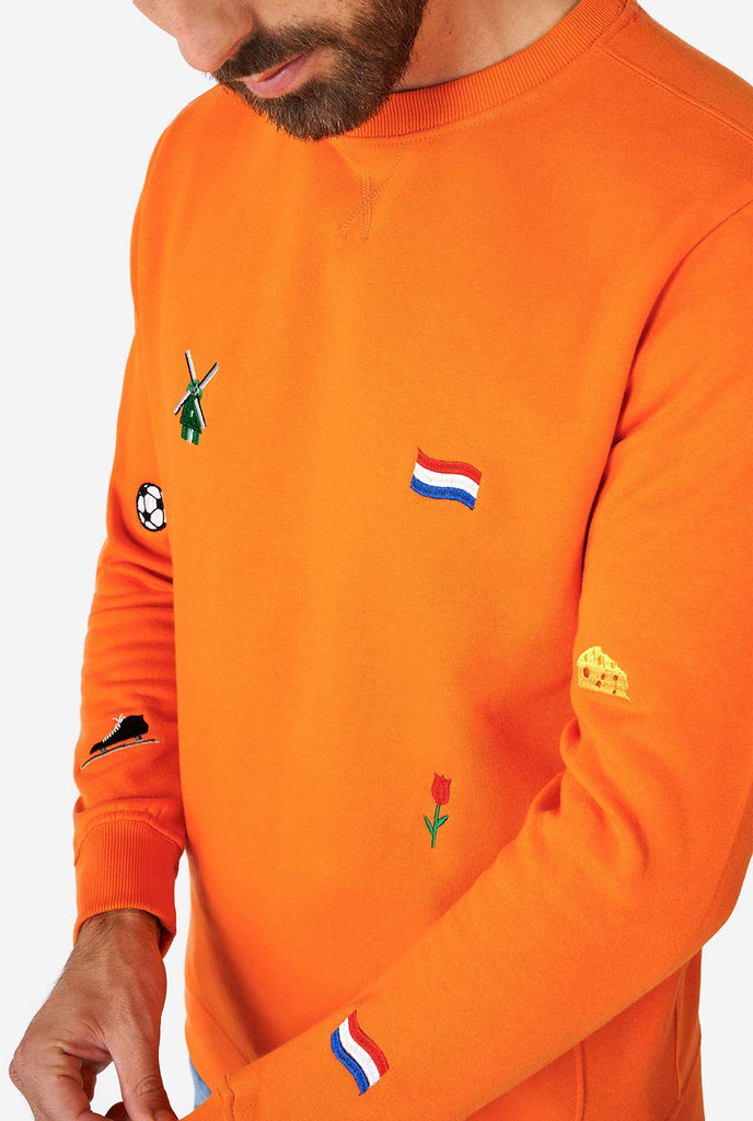 Mann trägt einen orangefarbenen Pullover mit niederländischen Ikonen