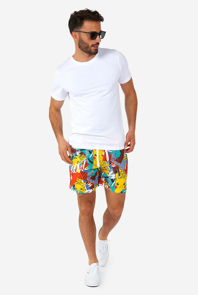 Mann, der bunte Sommershorts mit Pikachu -Pokemon -Druck und Weißen Shirt trägt