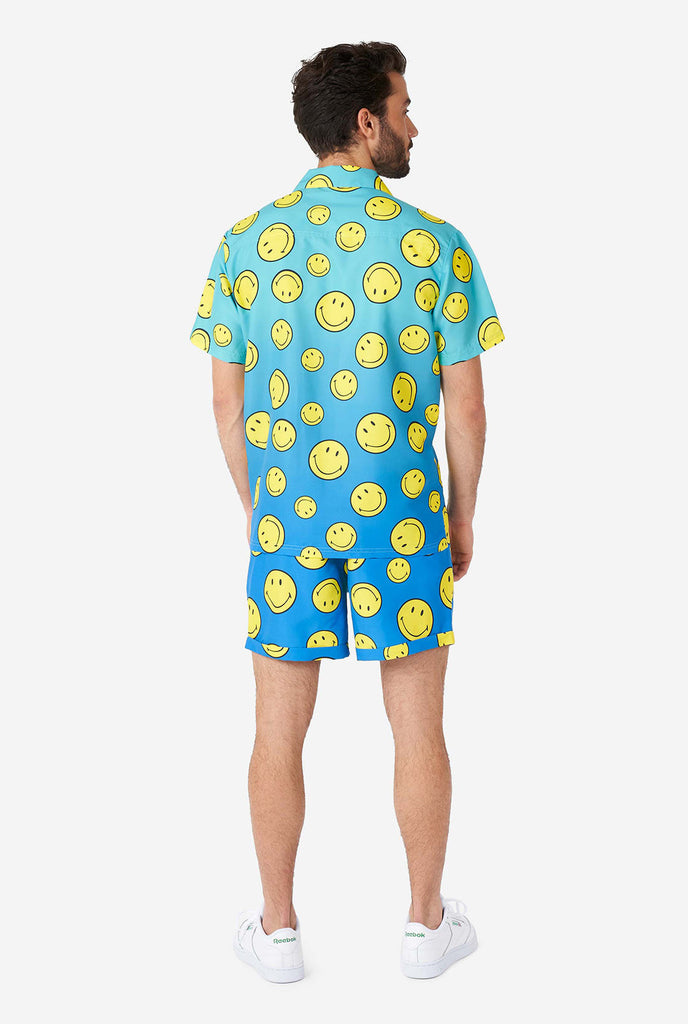 Mann, der blaues Sommerset trägt, bestehend aus Shorts und Hemd, mit Smiley -Druck, Blick von hinten