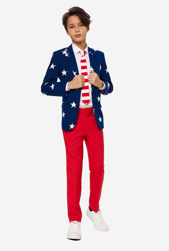 Teenager, der einen formellen Anzug am 4. Juli mit dem offiziellen USA farben trägt, bestehend aus blauer Jacke und roten Hosen.