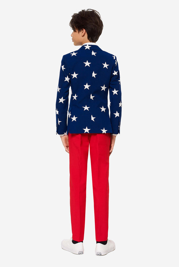 Teenager, der einen formellen Anzug am 4. Juli mit dem offiziellen USA farben trägt, bestehend aus blauer Jacke und roten Hosen., Blick von hinten
